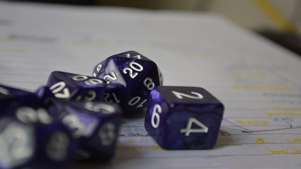 Top-down view of players around a strategic tabletop board game map with colored pieces and cards